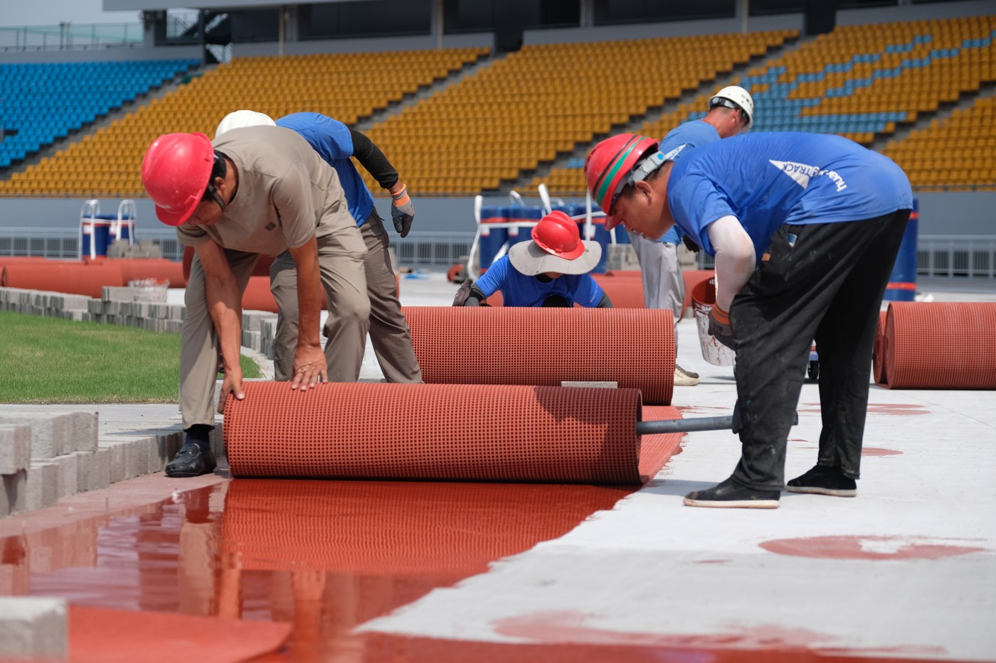 HUADONG installation team unrolling prefabricated rubber track material over adhesive